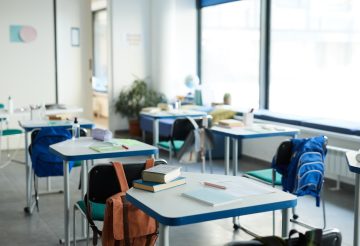 Background image of desks in row with textbooks and supplies in school classroom interior, copy space